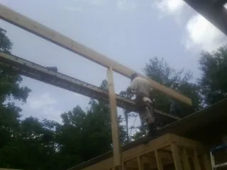 Carpenter setting a ridge beam over a new addition frame — Ice Dam Removal by Roofing Brothers in Birmingham