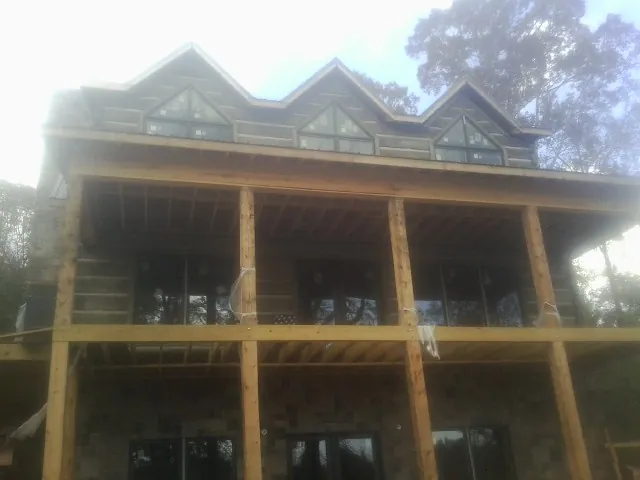 Dormers and porch framing on a large log home under construction — Roof Coating work by our crew in Birmingham